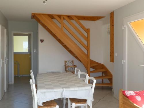une salle à manger avec une table et un escalier dans l'établissement Gîte neuf au calme près de Gérardmer avec terrasse et balades en forêt - FR-1-589-217, à Le Tholy