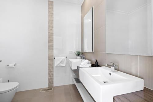 a white bathroom with a sink and a toilet at Serendib Luxury Sorrento Resort Living in Sorrento