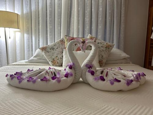two swans dressed in flowers are sitting on a bed at Exclusive Altos del Maria 2 Bedroom Apartment-Private Pool & Mountain Views in Sorá