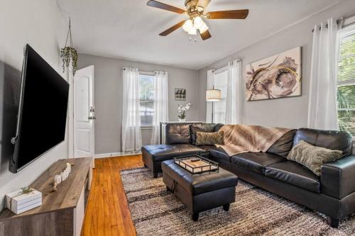 a living room with a leather couch and a flat screen tv at East Hill Retreat Near Beaches & Downtown in Pensacola