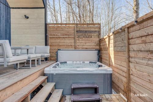 a jacuzzi tub on a wooden deck with chairs at Villa Rosa Madha - Scandinave - Cosy avec spa in Sainte-Catherine