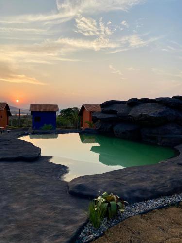 a pool of green water next to a large rock at Pousada Pôr do Sol in São João Batista do Glória