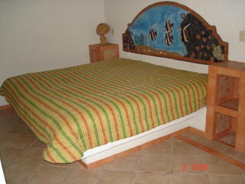a bed in a bedroom with a bedspread on it at BONITO APARTAMENTO RODEADO DE PALMERAS primer nivel in Barra de Navidad