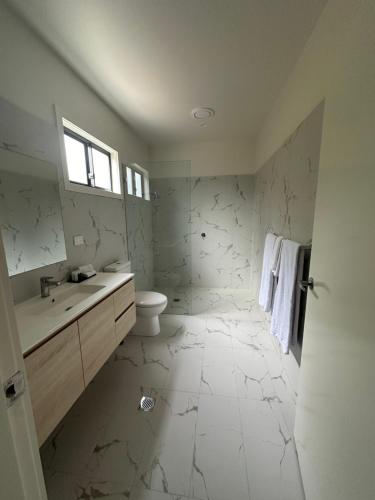 a white bathroom with a sink and a toilet at Fitzroy Inn Historic Retreat Mittagong in Mittagong