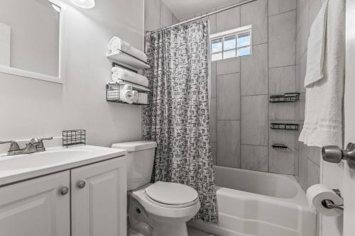 a white bathroom with a toilet and a shower at East Hill Manor with 2 Kitchens Near Beach & Downtwn in Pensacola