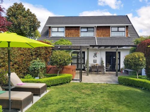 a house with a patio and an umbrella at Haven Homestay Rotorua in Rotorua