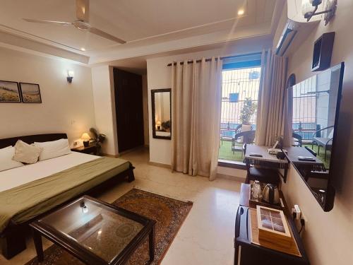 a bedroom with a bed and a desk and a window at Niro GK2 in New Delhi
