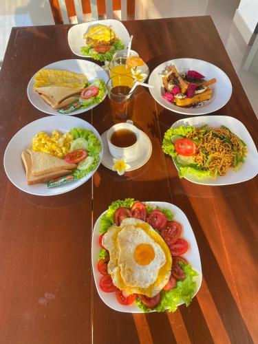 a table with plates of breakfast food on it at Maskot Penida Cottage in Nusa Penida
