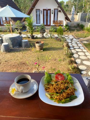 a plate of spaghetti and a cup of coffee on a table at Maskot Penida Cottage in Nusa Penida