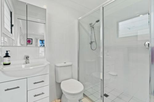 Un baño blanco con inodoro y ducha. en Jado on the Lake, Jervis Bay, en St Georges Basin