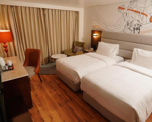 a hotel room with two beds and a desk at Hyatt Centric Rajpur Road Dehradun in Dehradun