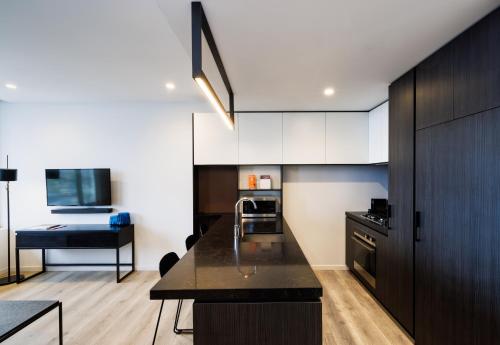 a kitchen with white cabinets and a black counter top at Avani Melbourne Box Hill Residences in Box Hill