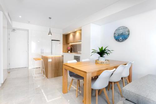a kitchen and dining room with a wooden table and chairs at Bokarina Beach Apartments, an Ascend Collection Hotel in Bokarina