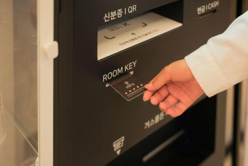 a hand is pressing a button on a vending machine at Hwaseong Stay13 Hotel in Hwaseong