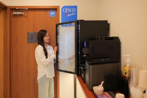 a woman is standing in front of a microwave at Hwaseong Stay13 Hotel in Hwaseong