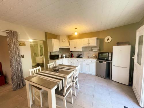 une cuisine avec une table et un réfrigérateur blanc dans l'établissement Gîte charmant à Montbazon avec terrasse, jardin et parking - FR-1-381-599, à Montbazon