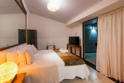 a bedroom with a large white bed and a tv at Casa Petunia Pousada Boutique in Salvador