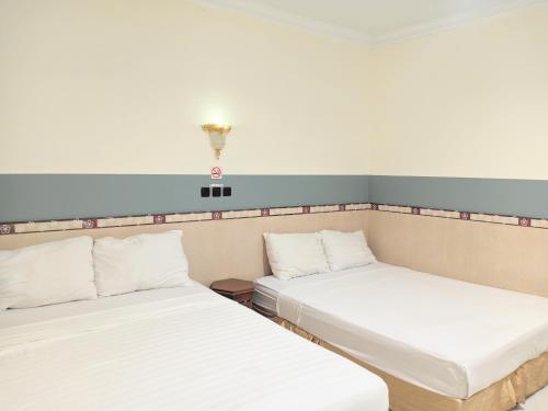 two beds in a room with a light on the wall at Musafira Hotel Syariah in Sentool