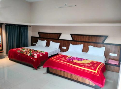 two beds in a hotel room with red blankets at Hetamji Villa in Mount Ābu