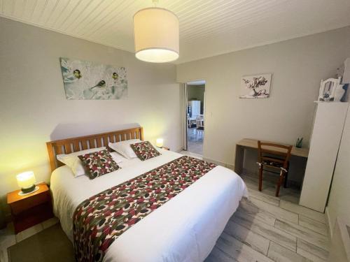 a bedroom with a large bed and a table with a chair at Gîte charmant à Montbazon avec terrasse, jardin et parking - FR-1-381-599 in Montbazon