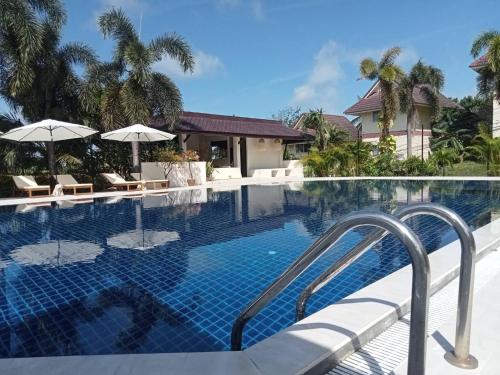 a swimming pool at a resort with chairs and umbrellas at Lanta Garden Hill Resort & Apartments in Ko Lanta
