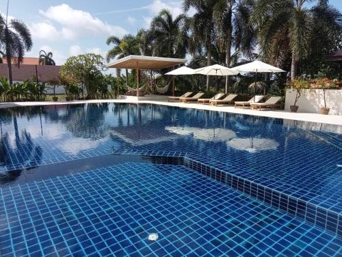 a large blue swimming pool with chairs and umbrellas at Lanta Garden Hill Resort & Apartments in Ko Lanta