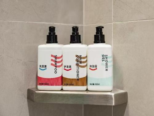 a group of three shampoo bottles sitting on a shelf at Echarm Hotel Guigang High-speed Railway Station Wuyue Plaza in Guigang