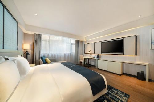 een hotelkamer met een groot bed en een flatscreen-tv bij Echarm Hotel Wuzhou Canghai Lake High Speed Railway Station in Wuzhou