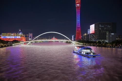 a boat on a river with a bridge at night at Yushe High-altitude Night View Hotel-Guangzhou Tower Zhujiang New Town Branch Exclusive for the Canton Fair in Guangzhou