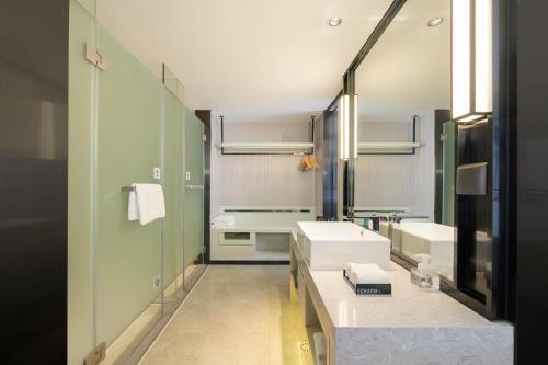 een badkamer met twee wastafels en een grote spiegel bij Echarm Hotel Wuzhou Canghai Lake High Speed Railway Station in Wuzhou