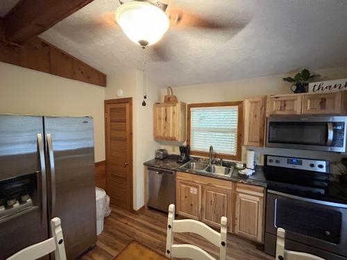 a kitchen with wooden cabinets and a stainless steel refrigerator at Tucked Away Cabin in Pigeon Forge