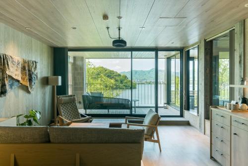 a living room with a couch and chairs and a balcony at HOTEL & KOTEI SOKA in Kyotango