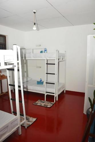 a room with two bunk beds and a red floor at Memo's Inn in Hiriketiya