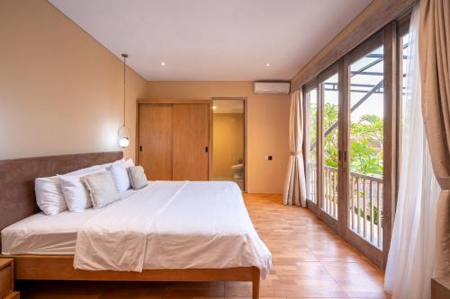 a bedroom with a large bed and a balcony at Villa Biku in Umalas