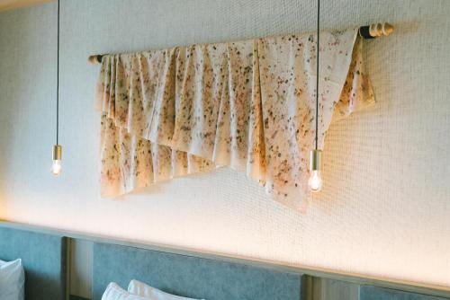 a curtain on a wall above a bed with two lights at HOTEL & KOTEI SOKA in Kyotango