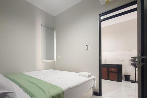 a white bedroom with a bed and a mirror at Urbanview Hotel at Pesona Guest House Jambi in Paalmerah