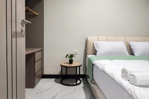 a bedroom with a bed and a table with a plant on it at Urbanview Hotel at Pesona Guest House Jambi in Paalmerah