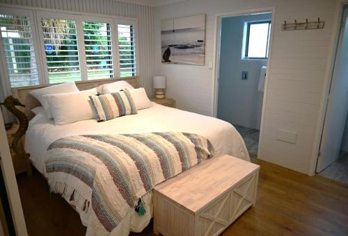 a bedroom with a bed and a table and windows at Bikini Bottoms by Experience Jervis Bay in Huskisson