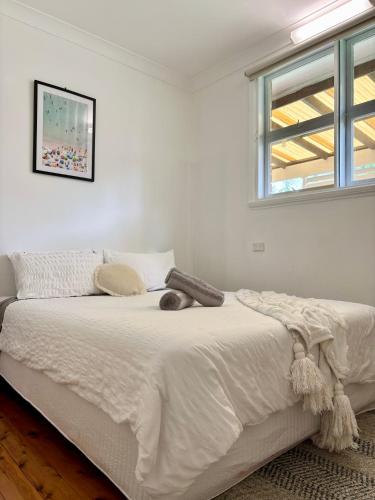 a bedroom with a white bed with a cat laying on it at Entire home on the beach in Shellharbour