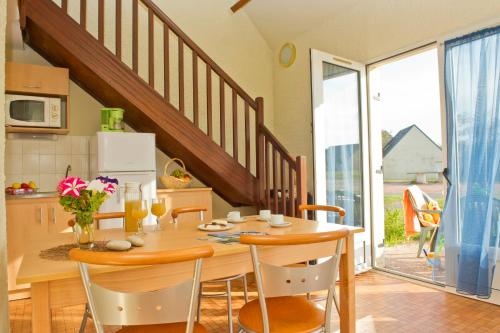 une cuisine avec une table en bois et des chaises ainsi qu'une salle à manger dans l'établissement VTF Le Sénéquet, à Blainville-sur-Mer