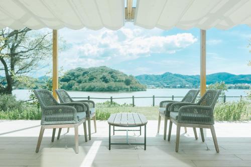 a group of chairs and a table in front of a lake at HOTEL & KOTEI SOKA in Kyotango