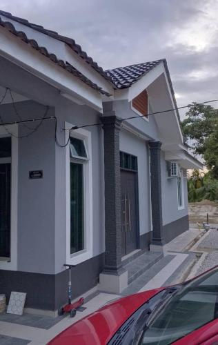 a small white house with a red car in front of it at AB Homestay Machang in Kampong Bechah Lara