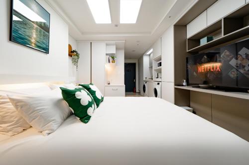 a bedroom with a large white bed and a television at Urbanstay Sokcho Deungdae Beach in Sokcho