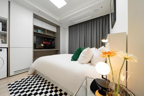 a bedroom with a white bed and a black and white checkered floor at Urbanstay Sokcho Deungdae Beach in Sokcho