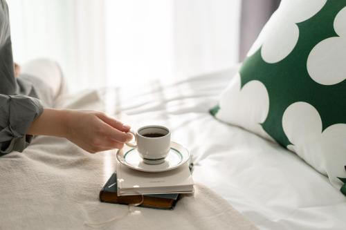 a person is holding a cup of coffee on a bed at Urbanstay Sokcho Deungdae Beach in Sokcho