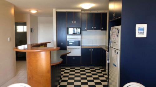 a kitchen with blue cabinets and a checkered floor at Sea Eagles Unit 4 in Caloundra