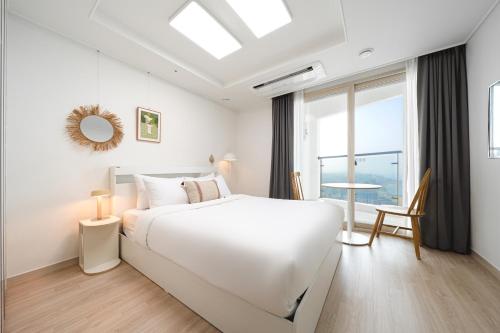 a white bedroom with a large bed and a window at Urbanstay Sokcho Deungdae Beach in Sokcho
