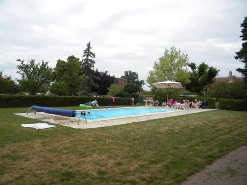a large swimming pool in a yard with people sitting around it at Grande maison avec piscine in Limoise