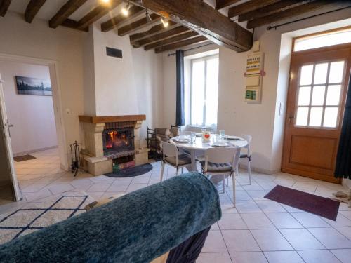 a living room with a table and a fireplace at Maison en Pays d'Othe in Les Sièges