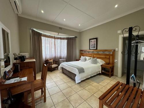 a bedroom with a bed and a table and a desk at Villa Beryl Guesthouse in Vryheid